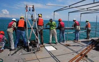 researchers on a ship doing sediment coring